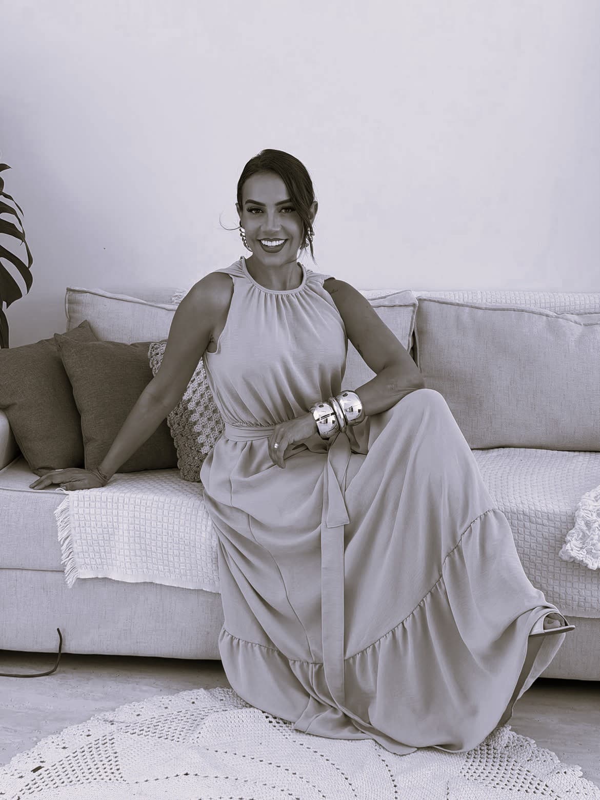 Manu Andrade sentada em um sofá, sorrindo